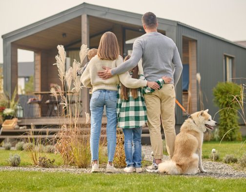 Family with children and dog standing with back to camera