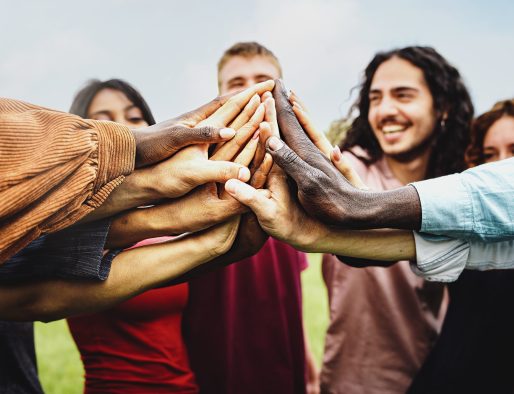 Joyful group of multi-ethnic community of happy people having fun joining hands in the park